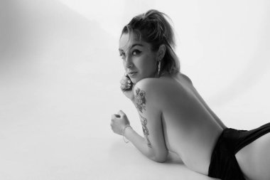 Beyaz arka planda dövmeleri olan seksi bir kadın.