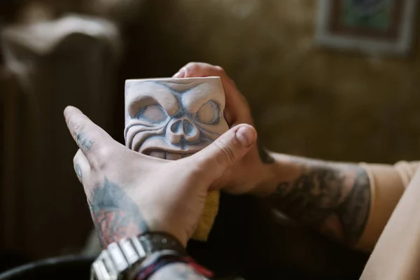 Tattooed man hands holding clay cup