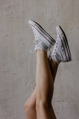 Beyaz spor ayakkabı giyen kadın bacakları.