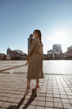 Şehirde gezen, trençkot giyen güzel, beyaz bir kadın.