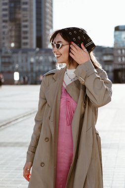 Şehirde gezen, trençkot giyen güzel, beyaz bir kadın.