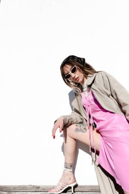 Trençkot ve pembe elbise giyen güzel beyaz bir kadın.