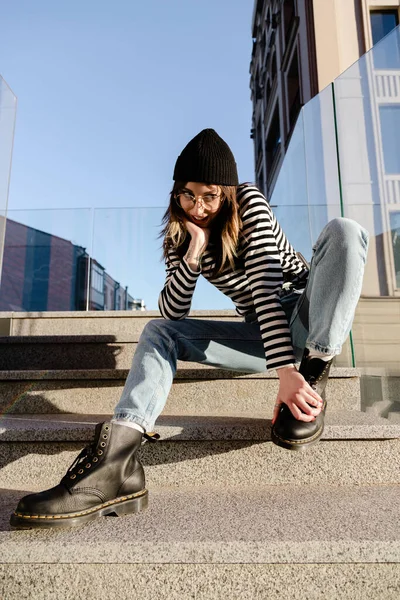 幸せな若いですCaucasian女性身に着けているジーンズとストライプベスト上の階段屋外 — ストック写真
