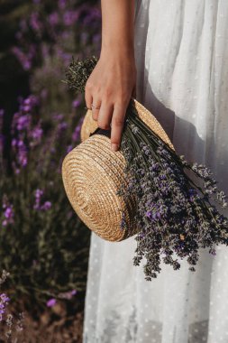 Lavanta buketi ve hasır şapka tutan kadın.