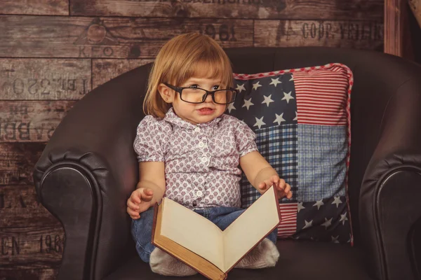Funny baby girl in glasses reading a book — Stock Photo, Image
