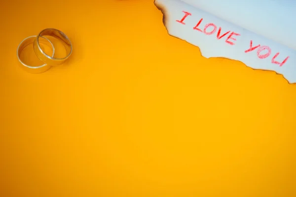 Love message and rings on yellow background — Stock Photo, Image