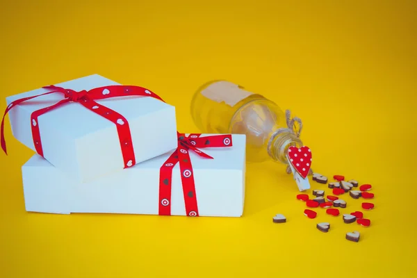 Κουτιά δώρων, καρδιές και μπουκάλι σε κίτρινο φόντο — Φωτογραφία Αρχείου