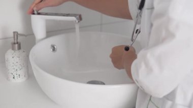 Kadın bir doktor hastayı aldıktan sonra ellerini sabunla yıkar..
