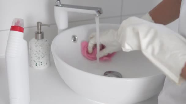 Gros plan, une femme de ménage dans les gants lave l'évier dans la salle de bain — Video