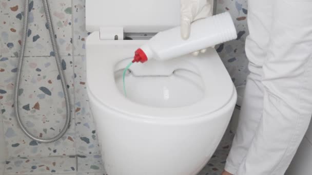A woman cleaning lady pours a cleaning product under the tank of the toilet — Stock Video