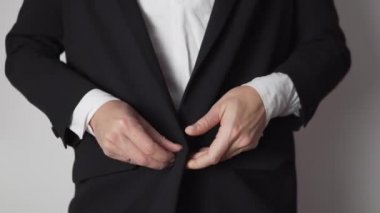 Bir kadın ceketin düğmelerini ilikler ve iş üniformasını düzeltir.