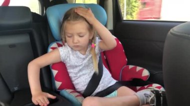 Küçük bir kız yazın bir araba koltuğunda kemerle gezer.