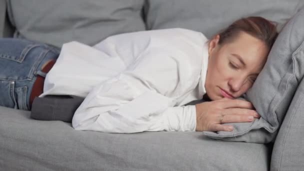 Uma mulher de negócios com uma camisa branca cai no sofá e adormece — Vídeo de Stock