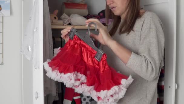 Mam hangt kleine dochters dingen in de kast aan de hanger en pakt een vrolijke outfit voor het nieuwe jaar en Kerstmis — Stockvideo