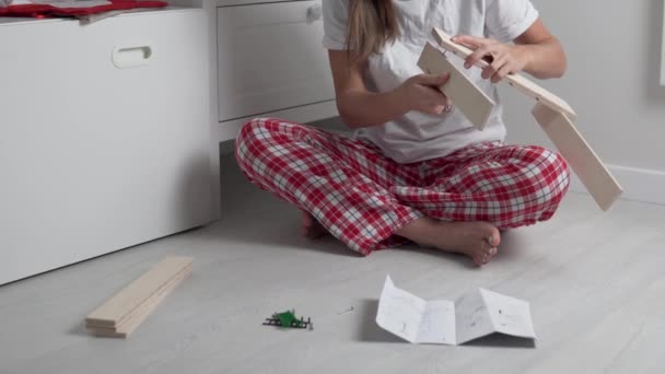 De vrouw verzamelt de houten plank van het huis volgens de instructies — Stockvideo