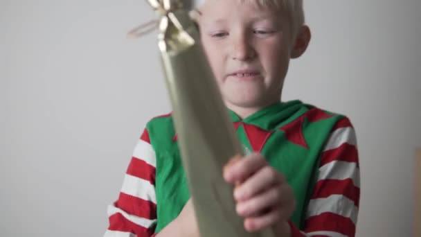 Blonďatý chlapec ve vánočním kostýmu rychle otevře vánoční dárek — Stock video
