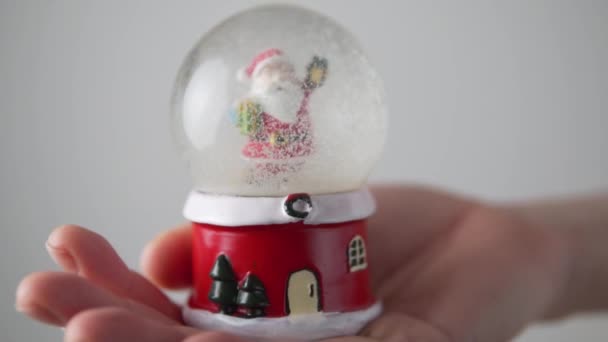 Gros plan, main féminine tenant une boule de verre jouet de Noël avec le Père Noël — Video