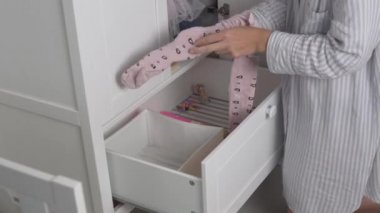 Anne, bir ev hanımı, evdeki küçük kızının dolabına tayt serer.