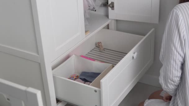 Мама аккуратно кладет вещи в шкаф своей маленькой дочери — стоковое видео