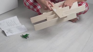 Noel 'de evde verilen talimatlara göre bir kadın çocuk oyuncakları için ahşap bir raf topluyor.