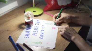 Noel gecesinde bir kadın renkli kalemlerle Noel Baba 'ya mektup yazıyor.