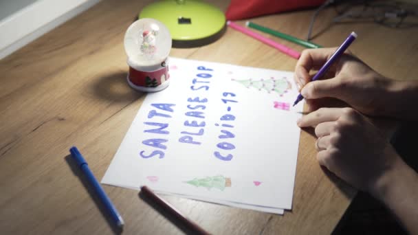Женская рука пишет плакат для Санта-Клауса с просьбой прекратить ковид-19 — стоковое видео
