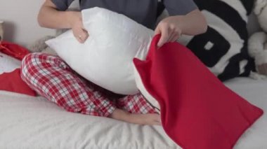 Bir kadın ev hanımı kanepe için yastığa yeni yıl örtüsü koyar.