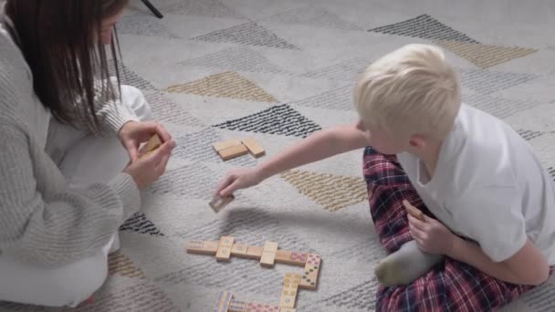 Mutter und Sohn spielen zu Hause in hölzernen Dominosteinen. — Stockvideo