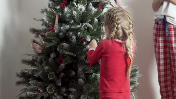 아이들과 엄마는 장난감으로 아름다운 크리스마스 트리를 장식 한다 — 비디오