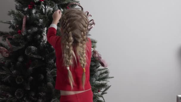 Küçük kız kardeşi olan sevimli erkek kardeş oyuncakları ve süslemeleri evde Noel ağacı ile süslüyor. — Stok video