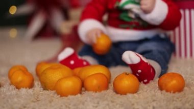 Noel takım elbiseli bir çocuk mandalinaların yanına oturur ve yılbaşında onların tadına bakar..