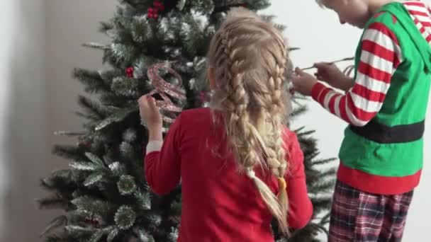 Uma mãe com filhos se veste com brinquedos e decorações árvore de Natal artificial em casa — Vídeo de Stock