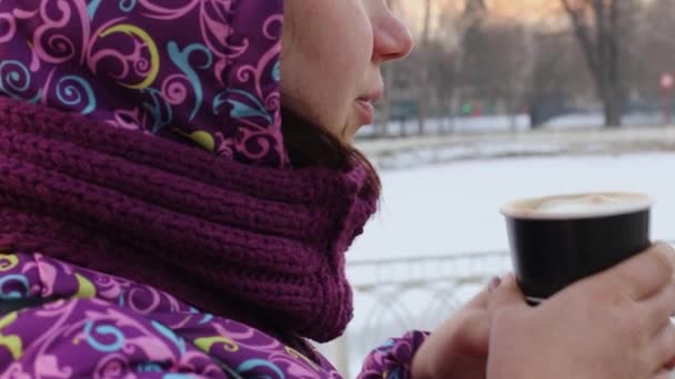 Een vrouw drinkt 's winters koffie op straat. — Stockvideo