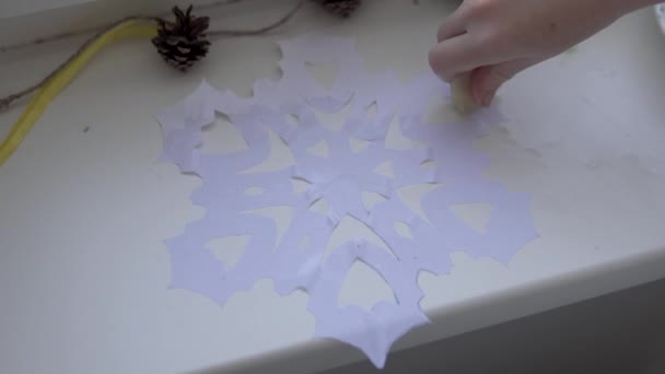 Das Kind schmiert eine Schneeflocke mit Seife, die sie auf das Fensterglas klebt — Stockvideo