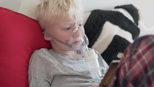 En stilig blond pojke behandlar lunginflammation i hemmet med hjälp av en hemmagjord nebulisator som gör ingoly med medicin — Stockvideo