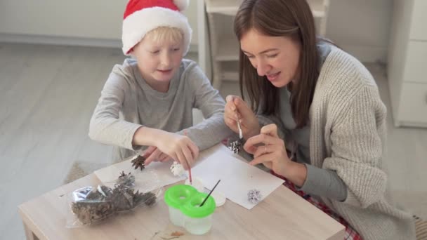 Mamá e hijo decoran con conos de abeto de pintura blanca para la tarea escolar en invierno — Vídeos de Stock