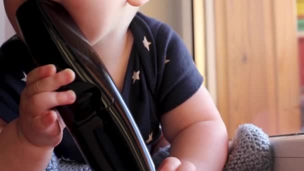 Baby licks and nibbles remote from TV at home — Stock Video