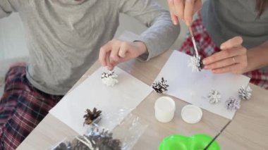 Anne ve oğul kışın evlerinde beyaz ladin kozalaklarıyla dekore ederler.