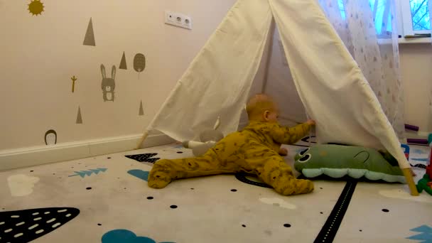 Un enfant se glisse dans une tente de jouets pour enfants dans une chambre d'enfant. — Video
