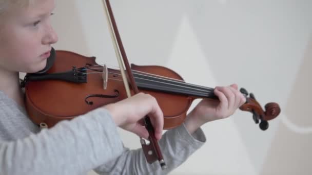 Menino loiro bonito aprende a tocar violino na nova casa — Vídeo de Stock