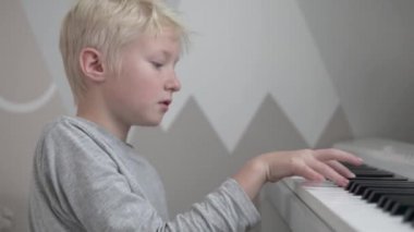 Evdeki elektronik piyanonun başında oturan yeni bir melodiyle ortaya çıkıyor..