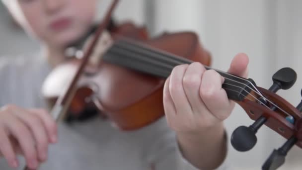 In Großaufnahme spielt der Junge zu Hause Geige, den Fokus auf seine Finger und das Mausinstrument — Stockvideo