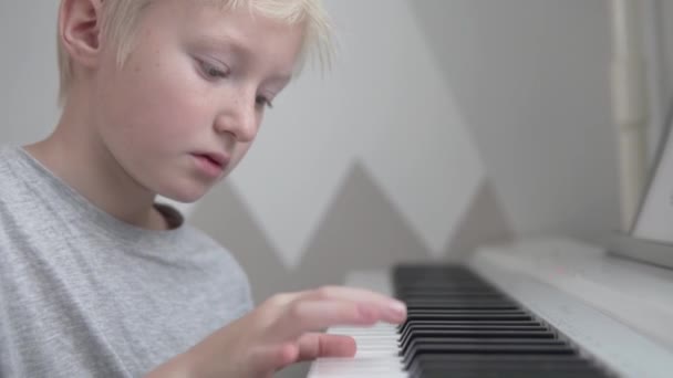 Primer plano, guapo chico rubio aprende a tocar el piano electrónico — Vídeo de stock