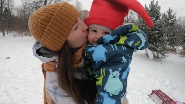 Närbild, en ung mamma leker med ett litet barn på gatan Vintern — Stockvideo