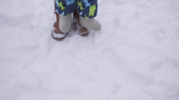 Eine Mutter mit einem kleinen Kind macht im Winter ihre ersten Schritte im Schnee — Stockvideo