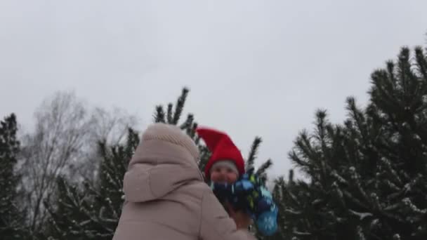 Mãe joga um pequeno bebê no inverno em uma caminhada — Vídeo de Stock