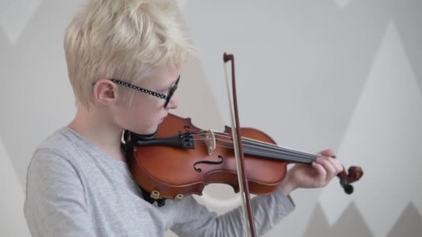 Un ragazzo biondo con gli occhiali impara a suonare il violino in una scuola di musica — Video Stock