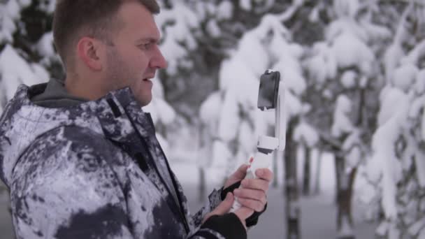 Гарний чоловічий блогер стріляє в мобільний телефон від поїздки до зими. — стокове відео