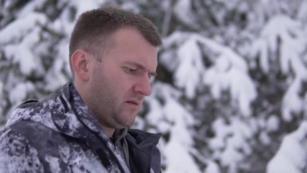 ハンサムな男性ブロガーは雪の森の中で冬にロシア北部への旅行中に生きる準備をしています — ストック動画