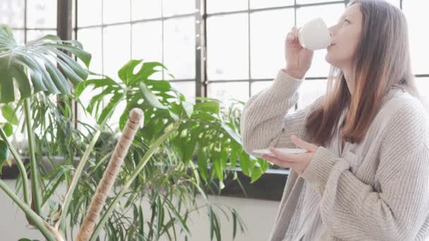 Una hermosa ama de casa bebe café por la mañana en casa — Vídeos de Stock